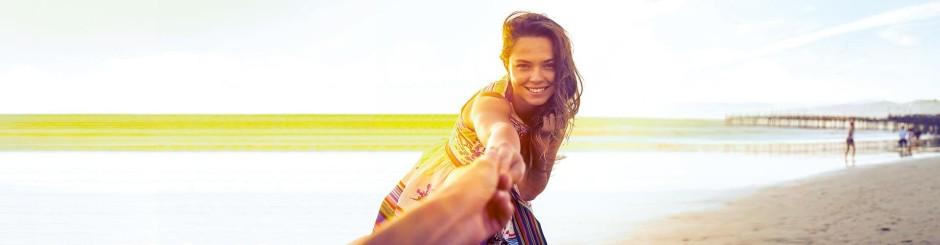 Frau am Strand bei Sonnenuntergang, hält Hand, freundliche Atmosphäre, Urlaub am Meer.