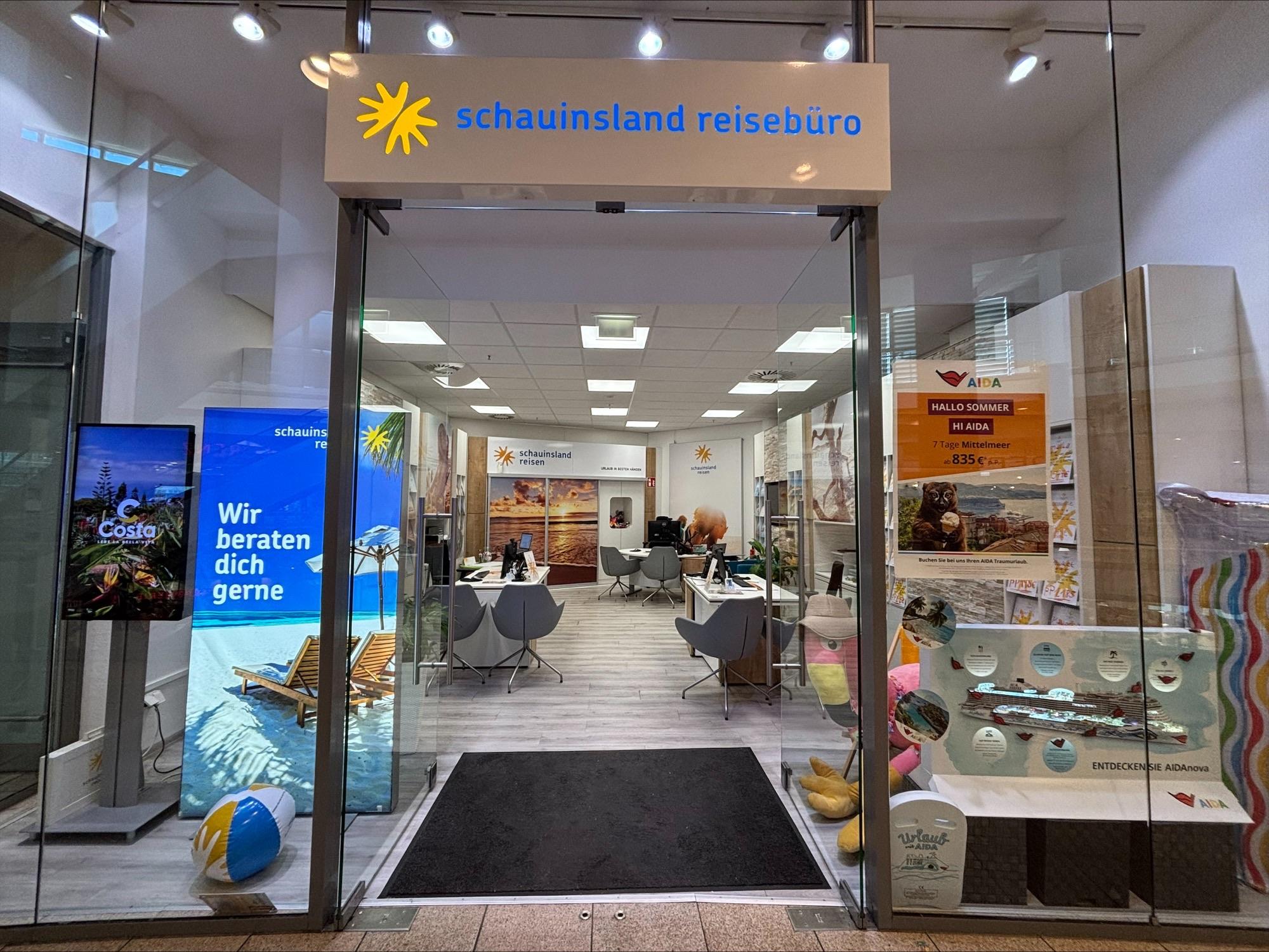 Modernes, helles Reisebüro mit Sitzgruppen, bunten Werbebannern und digitaler Beratung zum Thema Urlaub.