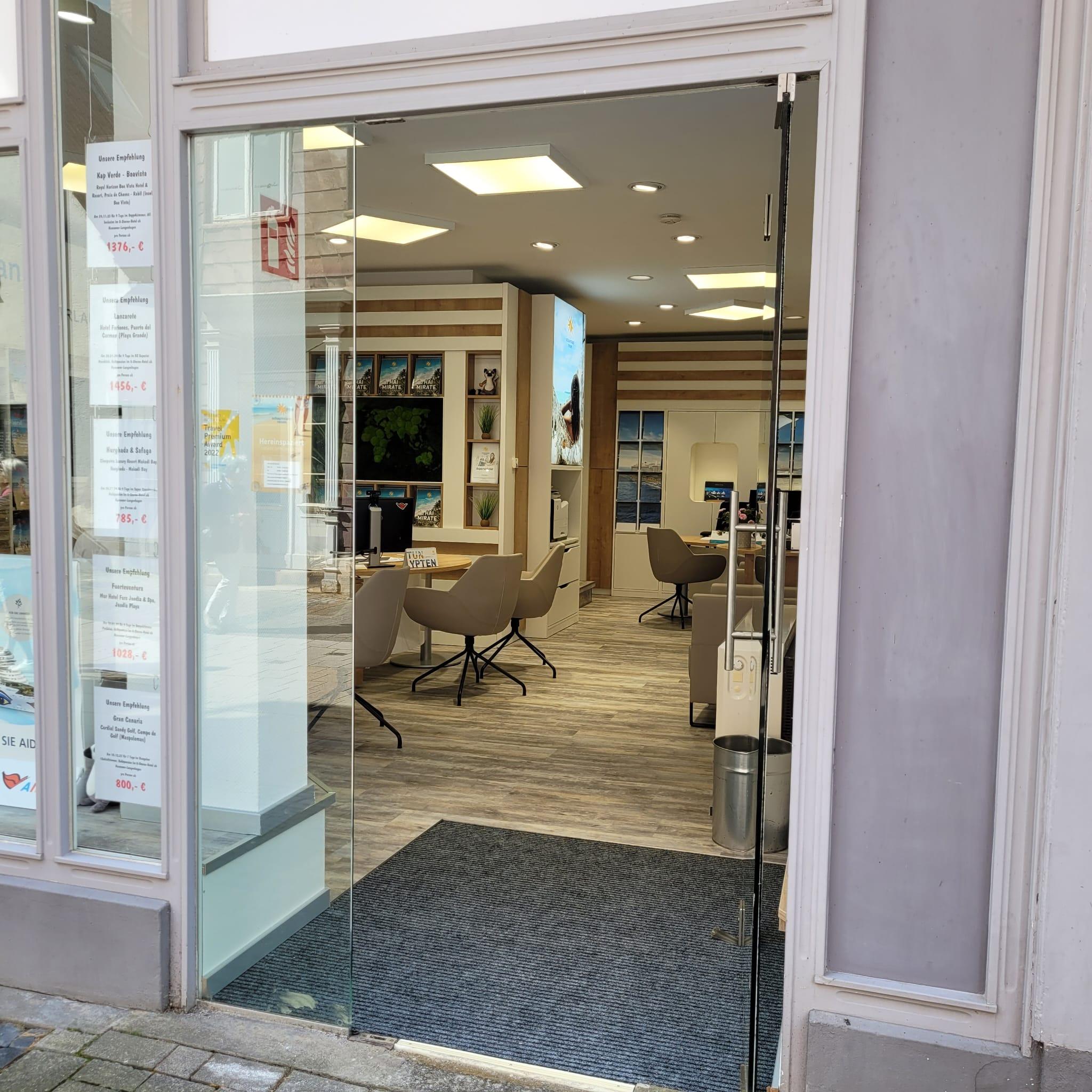 Offenes, modernes Reisebüro mit bequemen Sitzplätzen, Holzboden und hellen Wänden.