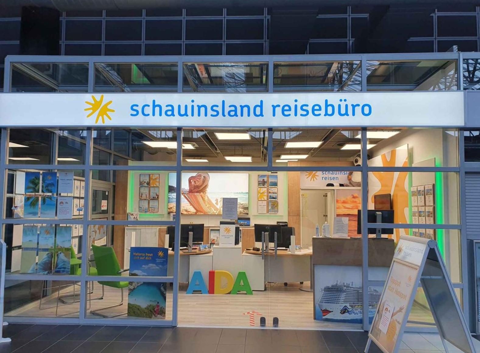 Modernes Reisebüro mit großer Schaufensterfront, hellen Innenräumen und Reiseangeboten für Urlaub.