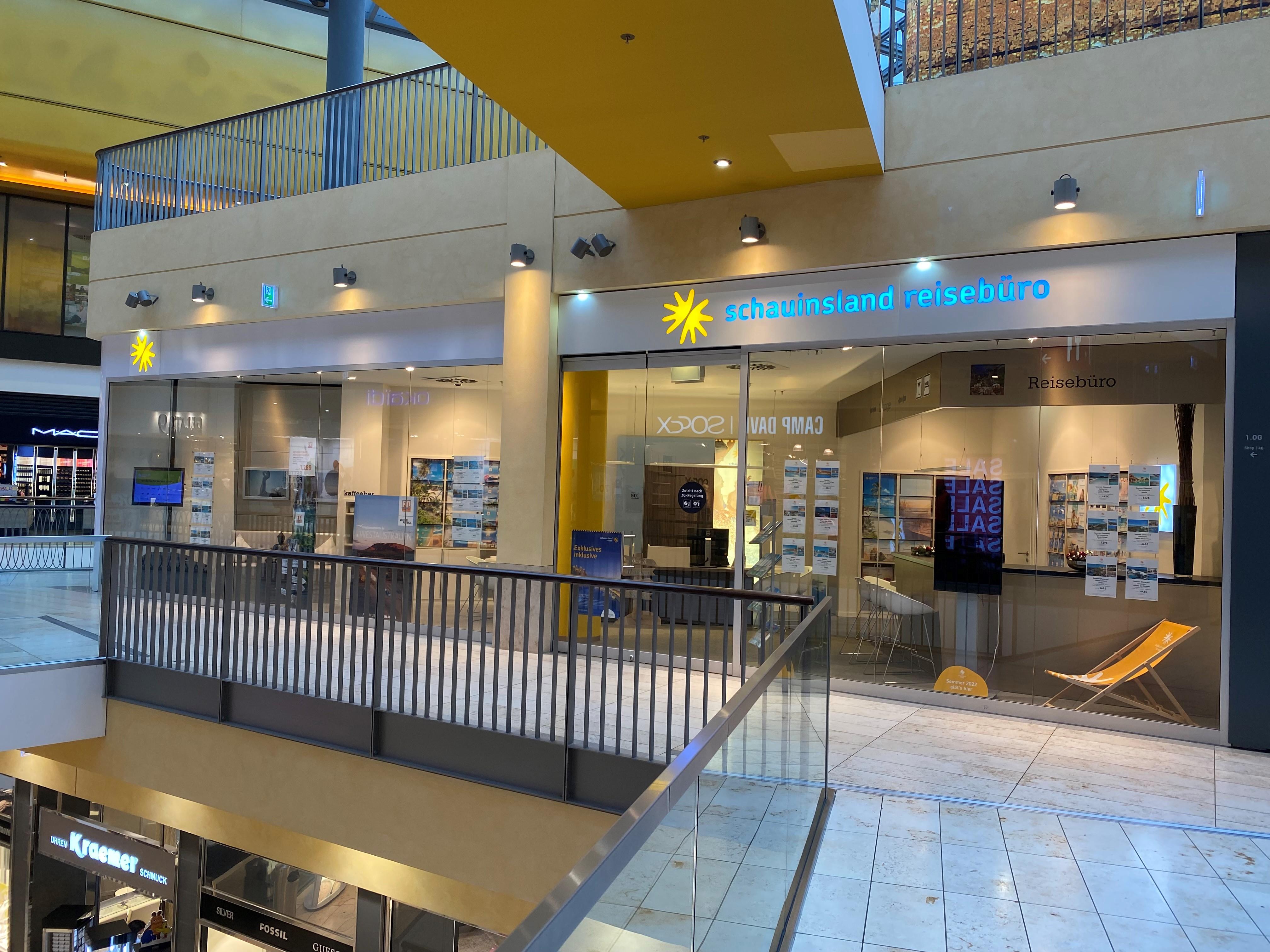 Modernes Reisebüro mit hellen Schaufenstern und Angeboten für Urlaub und Hotels im Einkaufszentrum.