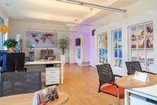 Helles, modernes Büro mit Holzfußboden, Sitzbereichen und bunten Bildern an den Wänden.