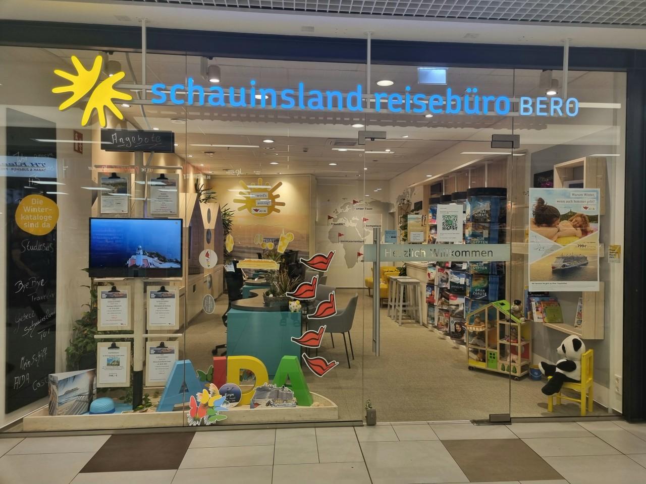 Modernes Reisebüro mit Glasfront, bunten Dekoelementen und Informationsmaterial zu Urlaubszielen.